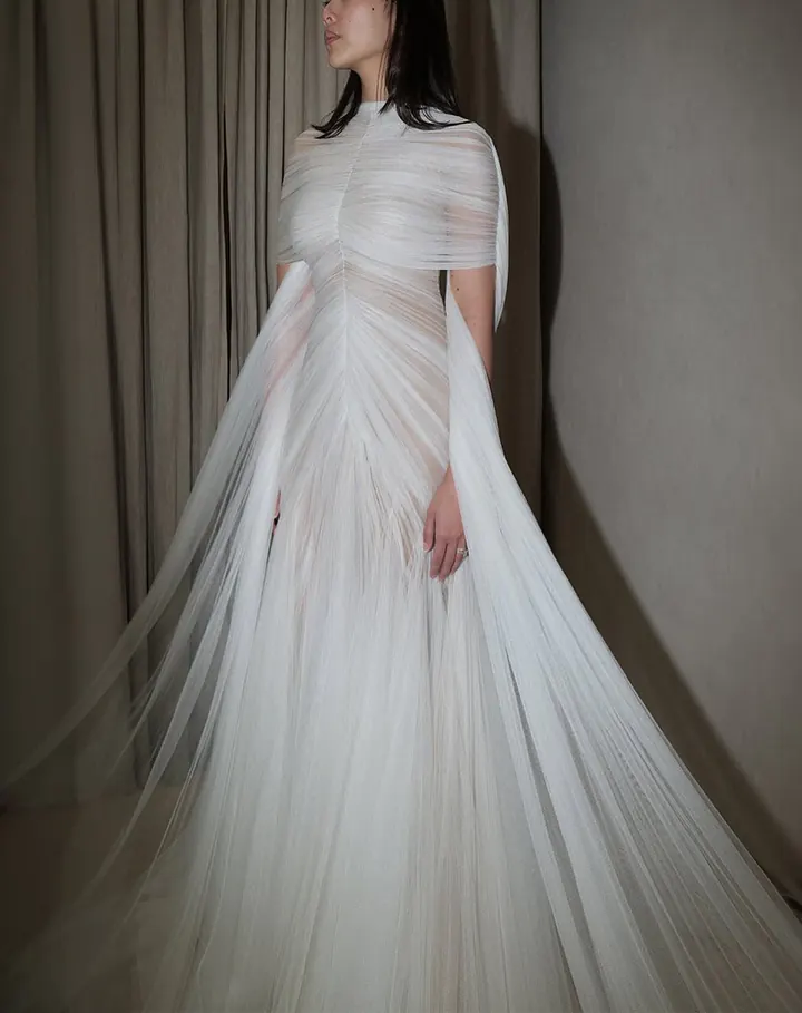 A gown of finely pleated ivory tulle that fans out from a gathered bodice into a full skirt