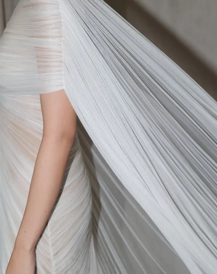 Close-up of fine ivory tulle pleated and gathered across the shoulder and arm